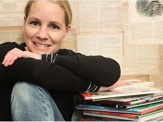 Petra Forster sitzt neben einem Stapel Bücher